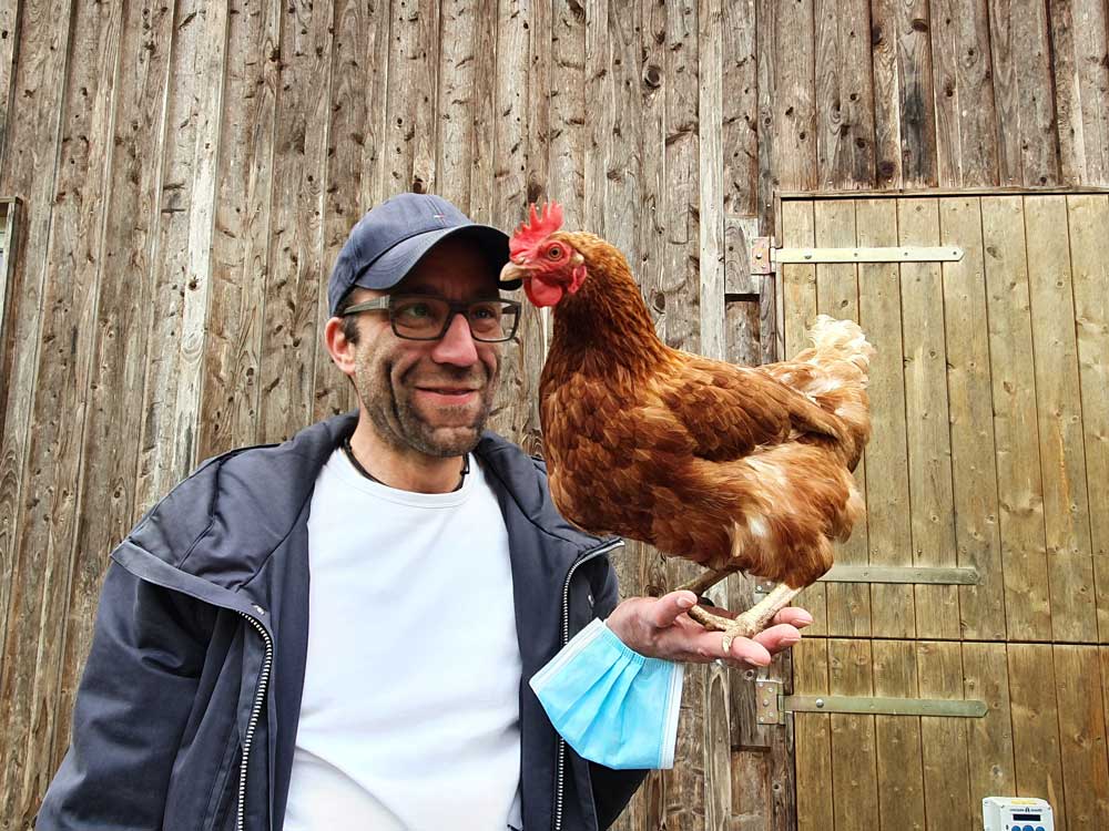 Ein Mann balanciert ein Huhn auf seiner Hand
